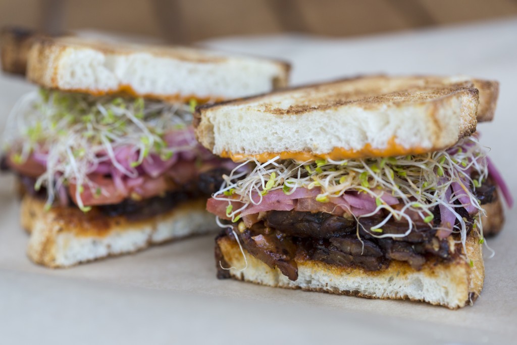 Smoky Sweet Hippie The Smoky Sweet Hippie: Double Maple-Glazed Tempeh Bacon, Alfalfa Sprouts, Tomato, Pickled Red Onions, BBQ Vegenaise on Toasted Rustic White - $8.95